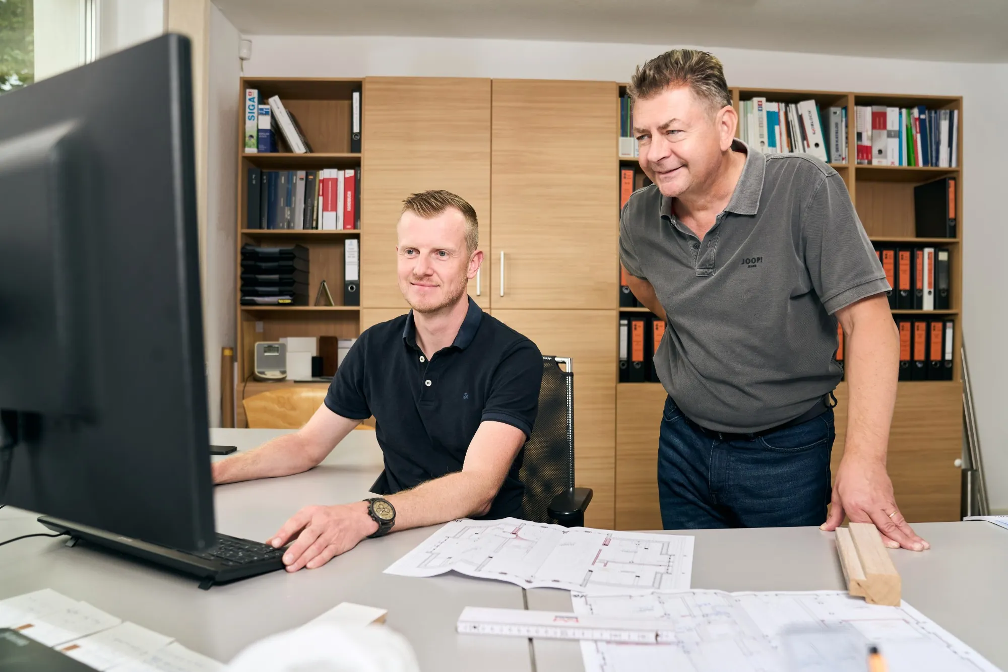 Zwei Kollegen der Bauabteilung besprechen Pläne am Bildschirm